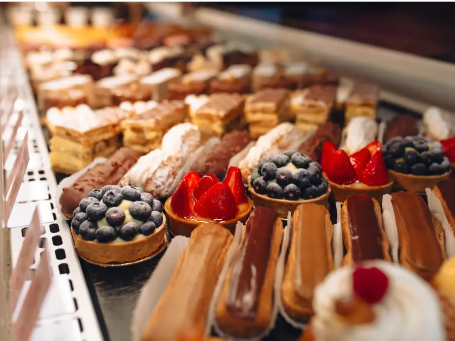 A pastry case of fruit tarts and individual mousse desserts