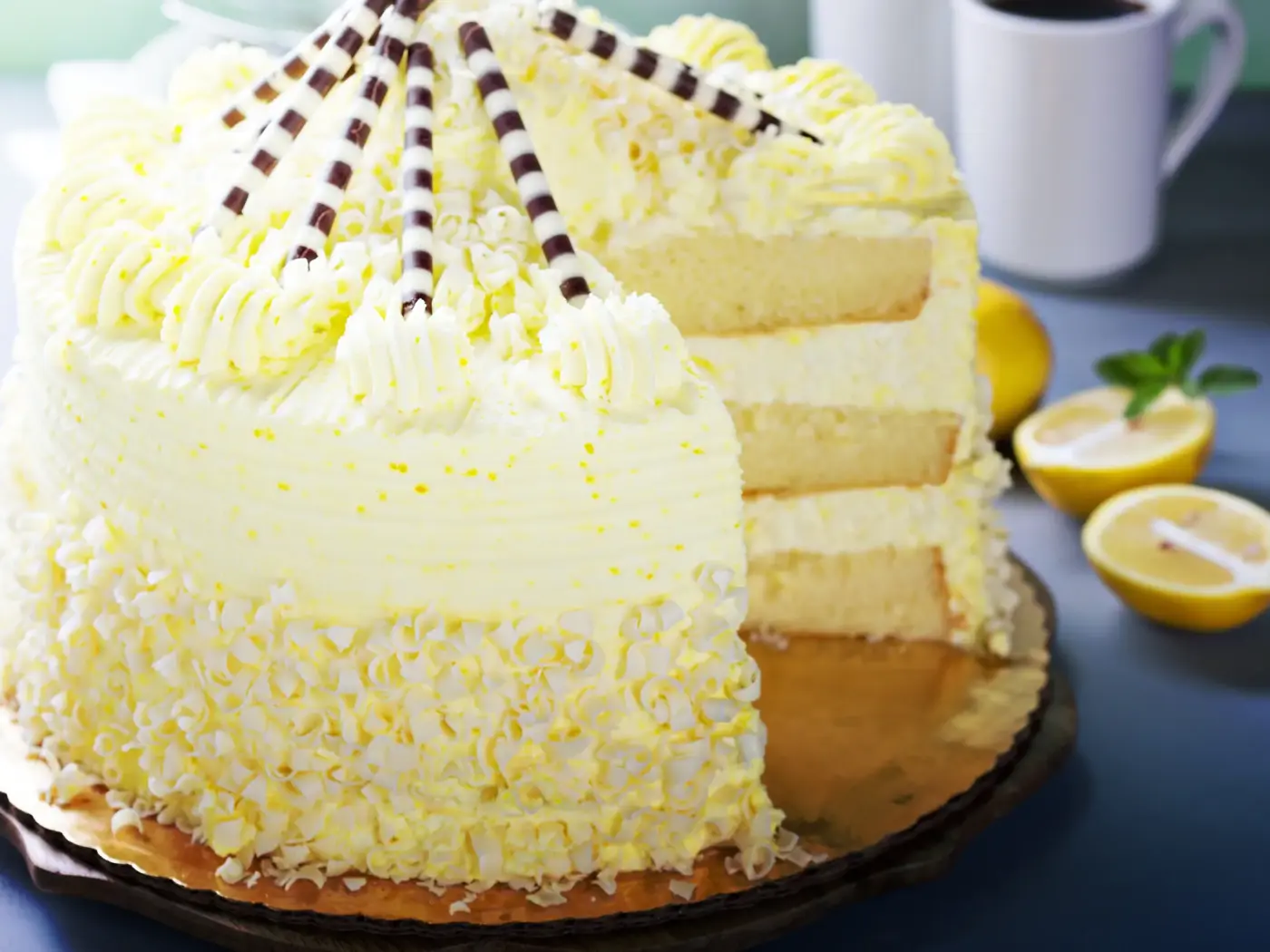 A frosted layer cake on a stand with one slice cut