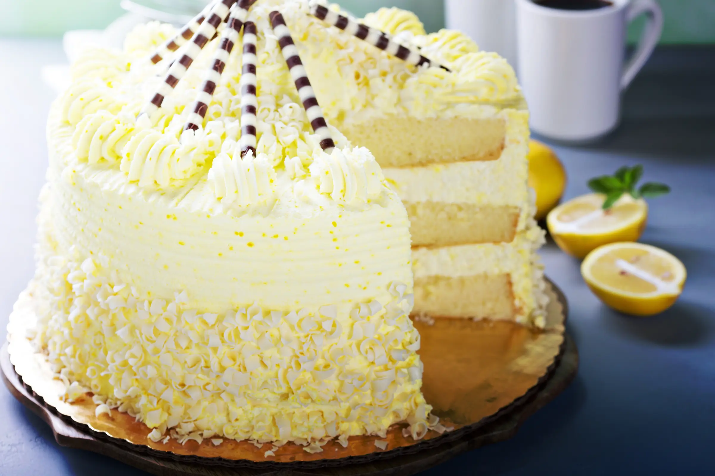 A frosted layer cake on a stand with one slice cut