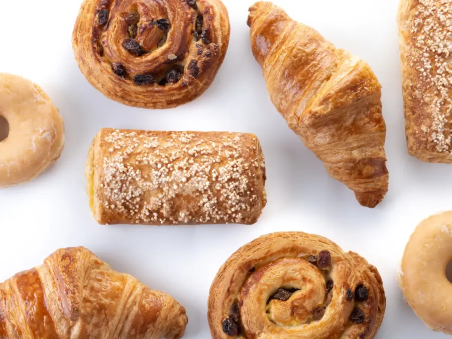Croissants, a cinnamon roll and a sugar-topped pastry on white