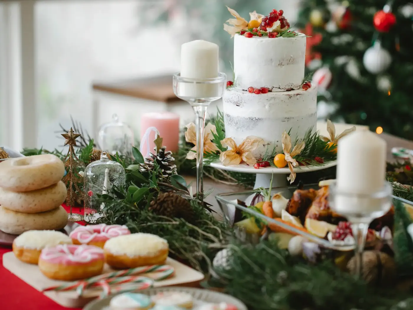 A tiered white celebration cake decorated with berries and greenery