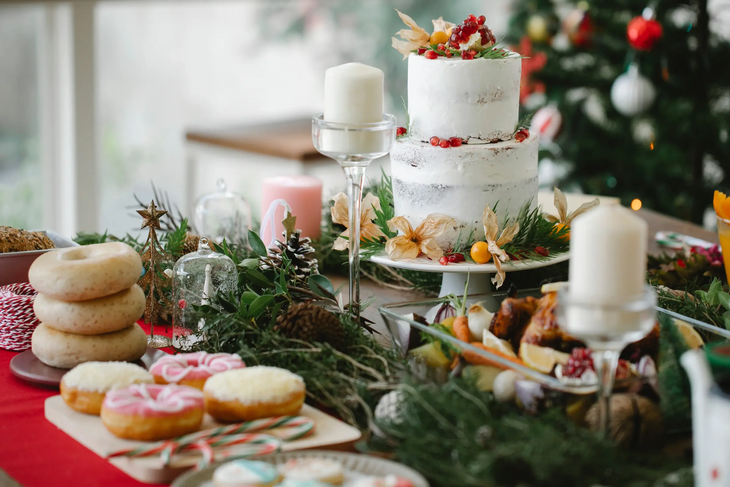 A tiered white celebration cake decorated with berries and greenery