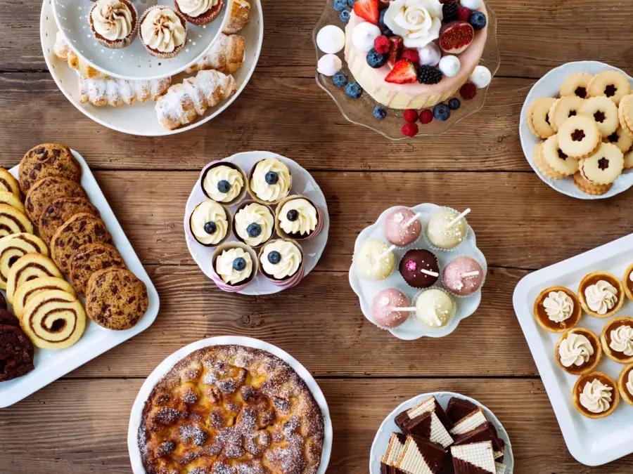 An overhead spread of cakes, cookies and mini desserts on a wood table