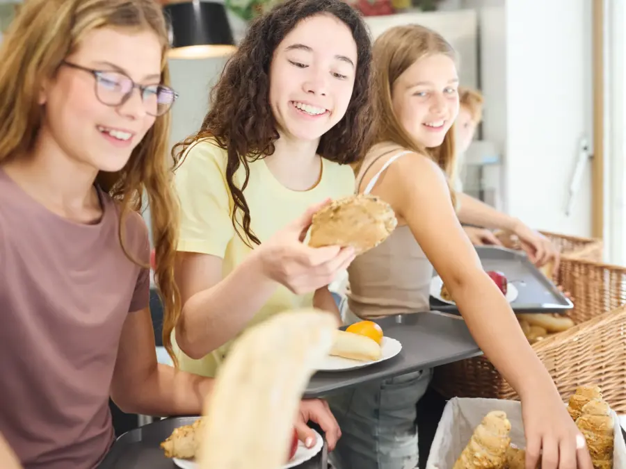 Three schoolchildren choosing food at a cafeteria line